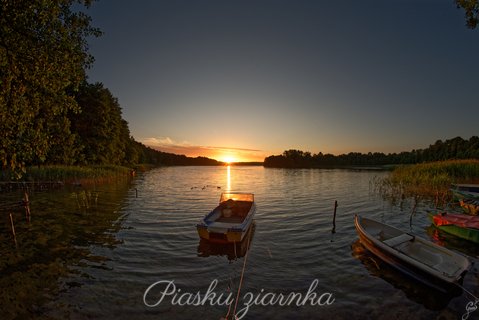 Łódka na jeziorze Pile na tle zachodzącego słońca